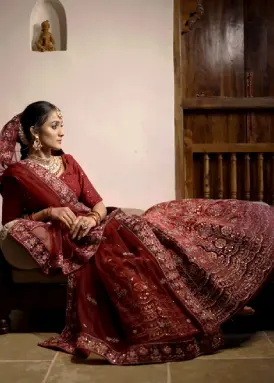 An Indian bride wearing a beautiful red lehenga from Dulhan, Pune sitting in a heritage home.